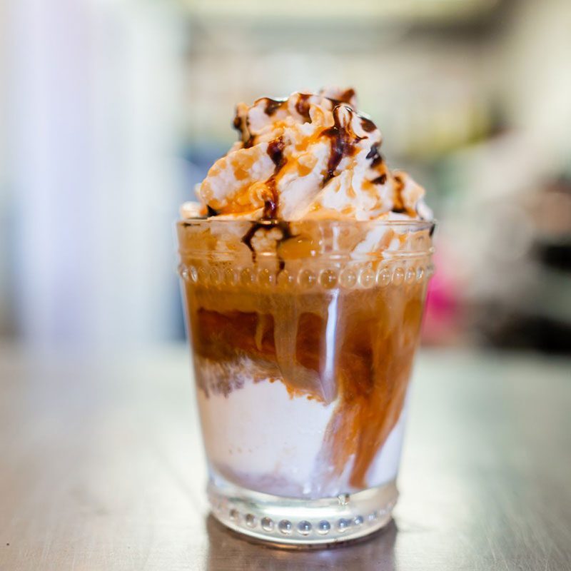 A glass of ice cream with whipped topping and chocolate.